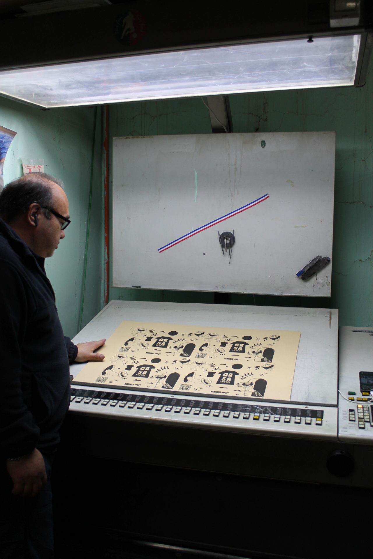 Operador revisando pliegos impresos bajo luz normalizada